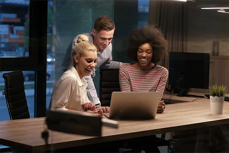 Three happy people using a notebook