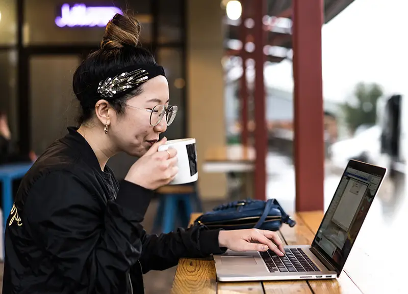 Lady drinking a coffee using a notebook